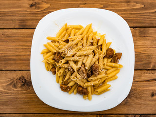 Italian cuisine, tasty short pasta dish with porcini mushrooms cheese and black pepper on wooden table outdoors for true epicureans