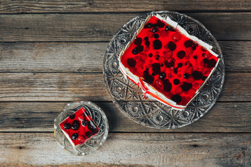 Berry cake and his piece on glass plates laying on a wooden table.