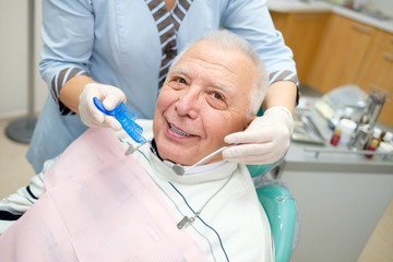 Closeup portrait of senior man in dental office sitting in dentist chair. Dental care for older people. Dentistry, medicine and health care concept