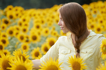 Young woman in sunflower field has fun