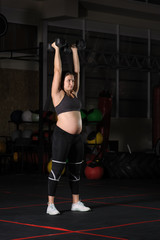 Pregnant female athlete doing dumbbell power snatch