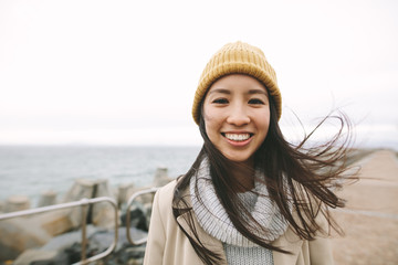Portrait of a smiling asian woman in winter clothes - obrazy, fototapety, plakaty