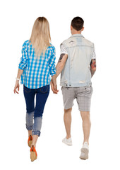 Fototapeta premium Back view of going couple. walking friendly girl and guy holding hands.