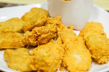 Fries chicken meat from fast food restaurant on white plate and blurry background.