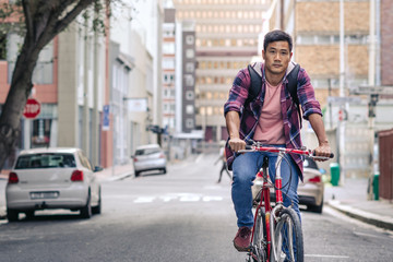 Young Asian man riding his bike through city streets