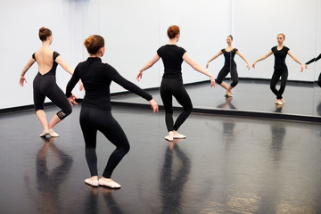 Fototapeta na wymiar Female Students At Performing Arts School Rehearsing Ballet In Dance Studio Reflected In Mirror