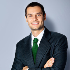 Happy businessman with crossed arms, on grey