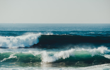 Dark waves with green and blue colours in sunny weather during the storm on the sea or ocean. Concept of nature beauty. Sunny seascape