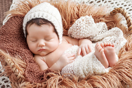 Beautiful little newborn baby 2 weeks sleeping in a basket with knitted plaid. Portrait of pretty  newborn baby