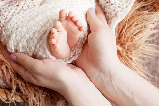 Newborn baby feet in mother hands. Mother holding legs of the kid in hands. Close up image. Happy family concept.