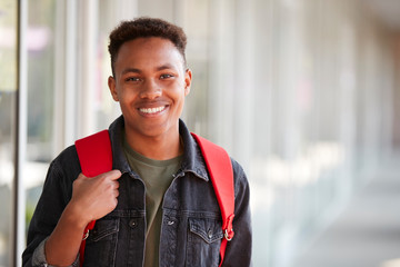 Portrait Of Smiling Male University Student With Backpack In Corridor Of College Building
