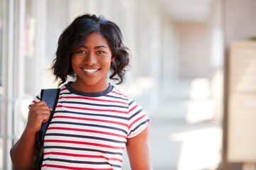 Portrait Of Smiling Female University Student With Backpack In Corridor Of College Building