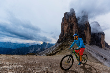 Cycling woman and man riding on bikes in Dolomites mountains andscape. Couple cycling MTB enduro trail track. Outdoor sport activity.