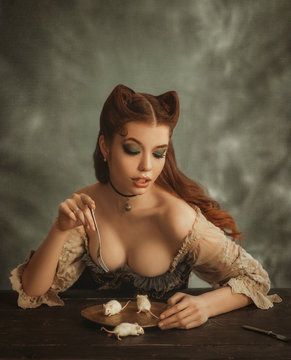 Fantasy woman cat. redhead lady with cat ears made of hair eats white mouse from golden dishes. pussycat eats cute animals. sexy lady in vintage dress, creative work of makeup artist and hairdresser