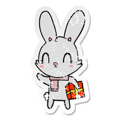 distressed sticker of a cute cartoon rabbit with christmas present