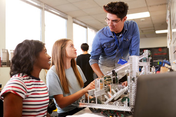 Teacher With Two Female College Students Building Machine In Science Robotics Or Engineering Class © Monkey Business