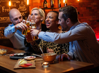 Group of friends watching tv in a cafe behind bar counter