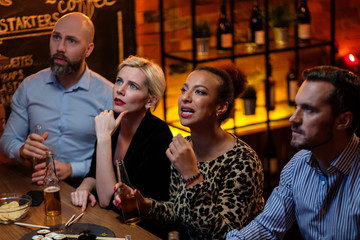 Group of friends watching tv in a cafe behind bar counter
