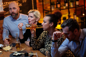 Group of friends watching tv in a cafe behind bar counter