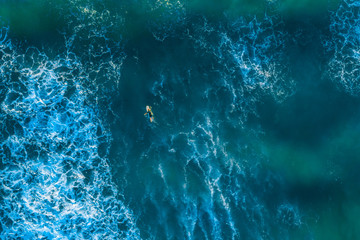 Fototapeta na wymiar Looking down at surfer in the ocean - aerial view