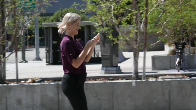 Young woman walks downtown while on her smartphone.