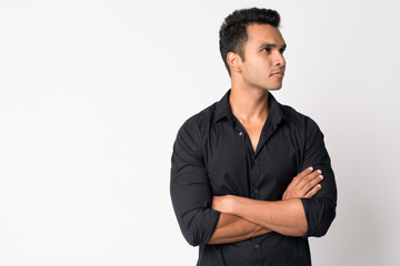 Portrait of young handsome Indian businessman thinking with arms crossed