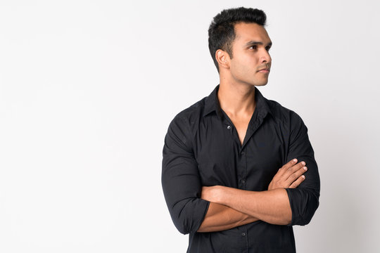 Portrait of young handsome Indian businessman thinking with arms crossed
