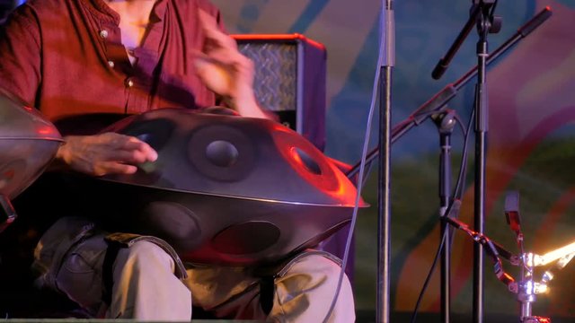 Man playing tank drum or hang on stage of ethnic open air concert. Relaxation, folk, meditative and traditional ethnic music concept