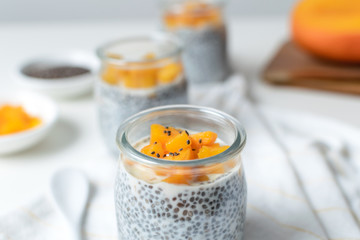 Fototapeta na wymiar Chia pudding in glass jar with almond milk and mango on white background
