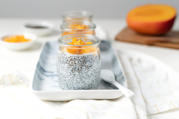 Chia pudding in glass jar with almond milk and mango on white background