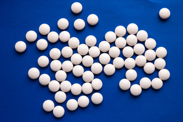 Scattering of white pills on the blue background.