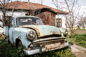 old abandoned retro car in the yard near the house