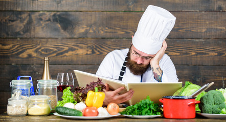 Man bearded hipster read book recipe near table fresh vegetables. Culinary arts. Recipe to cook...