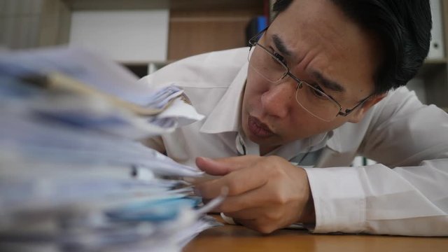 Businessman looking stack many paper document work overload in office