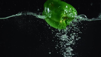 studio shoot of colorful green bell pepper dipping into clear water on black background - Powered by Adobe