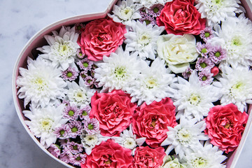 Gift box with heart shaped flowers on grey marble background