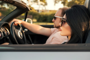 Gorgeous sexy copule of man and woman on a vacation car trip in summer day. Luxury grey sport car....