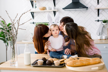 Cute Little Girl with rabbit ears on her head and Her Beautiful Mom, Aunt and Grandmother are eating cupcakes which they hold in their hands. Easter holidays or mothers day