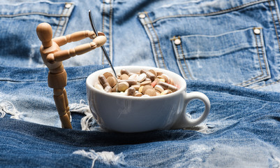 Health problem. Immunity and medicine vitamins. Mixing medicines. Fast treatment. Medicine prescription. Wooden human dummy near cup full pills and tablets. Take medicine concept. Vitamin cocktail
