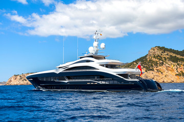 Luxury large super or mega motor yacht in the blue sea near the mountains.