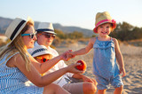 Laughing family with father, mother, daughters having picnic at the beach