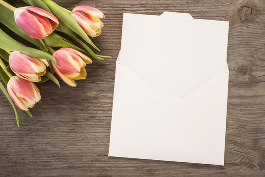 White envelope and flowers on wooden background