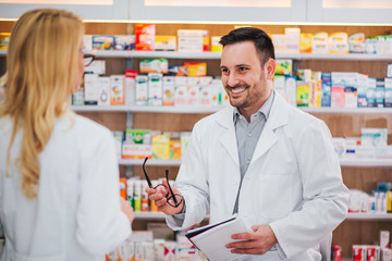 Male pharmacist talking to his female trainee.