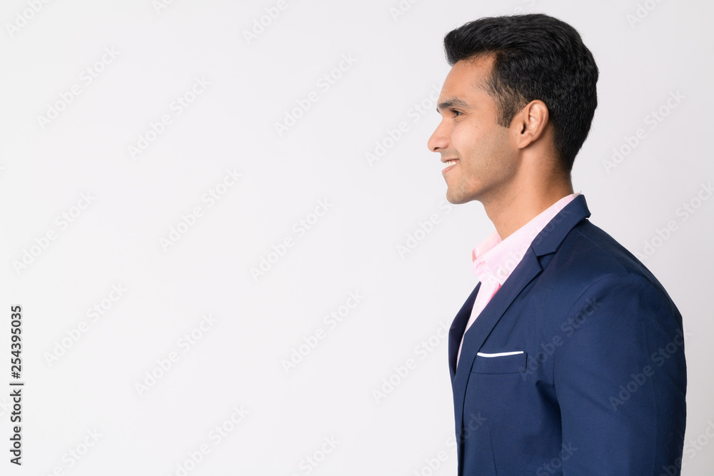 Wall mural Profile view of young happy Indian businessman in suit smiling