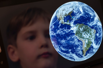 Reflection of a young boy looking at the earth on a tablet computer themes of science discovery awe Created with a Public Domain image from NASA