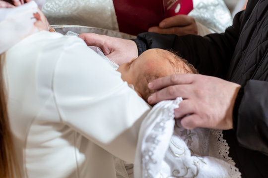 A fragment of a photograph of a little boy preparing for a baptismal ceremony, legs on a white blankets, baptism