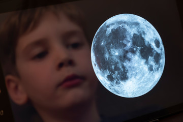 Reflection of a young boy looking at the moon on a tablet computer themes of science discovery awe Created with a Public Domain image from NASA