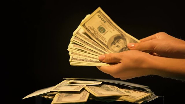 Hands holding bundle of dollars, money laundering, illegal business, kickback
