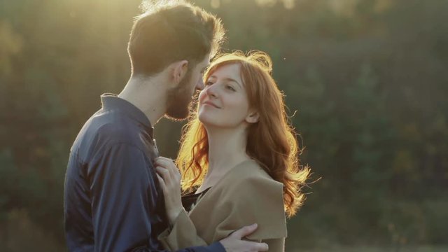 Happy couple stands in embrace and kisses each other on sunset