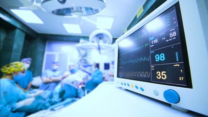 a group of surgeons operate on the patient's vital functions monitor close-up.
